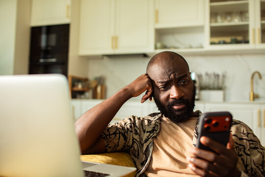 Man frowning at smartphone at home