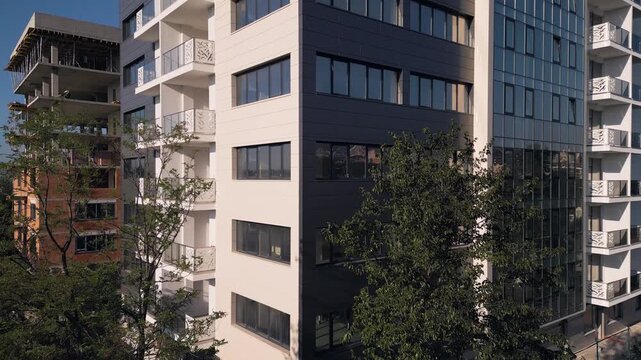 Modern apartment building facade next to construction site under clear sky