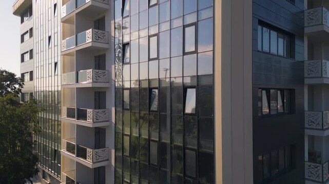 Modern residential building facade with glass reflections and decorative balconies