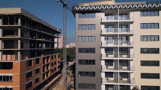 Modern apartment building facade next to construction site under clear sky