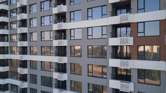 Modern apartment building facade with white balconies and glass reflections