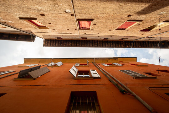 Bologna, Italy - 17 May 2018: View of historic orange buildings with open shutters and architectural details in the city center.