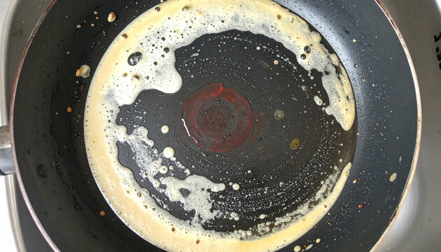 使用後のフライパンに残った油汚れのクローズアップ
Close-up of greasy residue left in a used frying pan