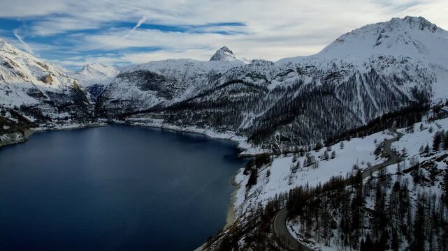Aerial drone view of an alpine lake surrounded by snowy mountains in winter