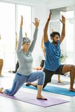 Stretching, woman or yoga class with low lunge, functional mobility or arms up for core stability. Mature yogi, group or exercise in wellness studio for hip flexor relief, mindful movement or fitness