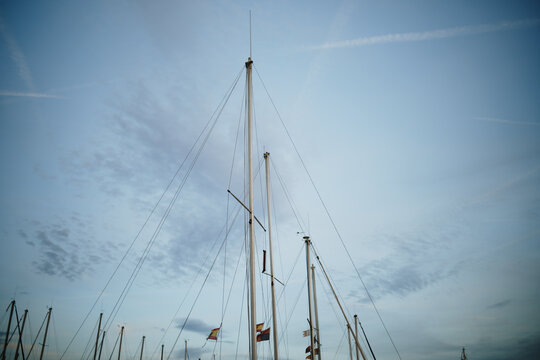 Port de Pollenca, Spain - 05 January 2025: View of sailboat masts against a blue sky with light clouds in the marina.