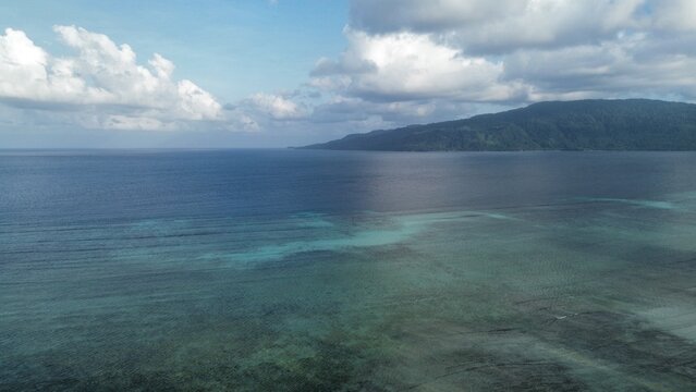 Aerial view of coral reef and turquoise ocean with mountain coastline in Teluk Sulaiman Berau East Kalimantan Indonesia