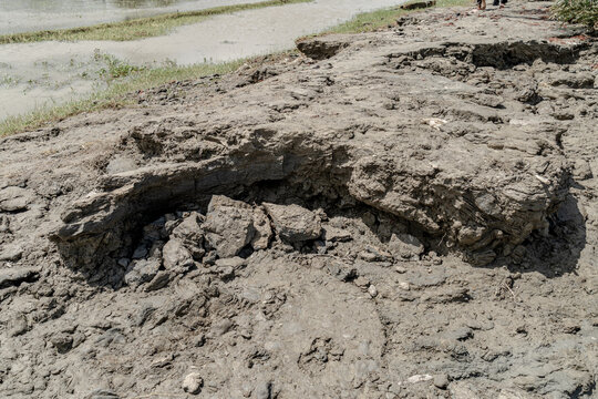 Noakhali, Chittagong Division, Bangladesh - 15 August 2026: View of riverbank erosion showing exposed soil layers and cracked mud along the river edge.