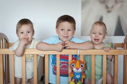Excitement fills the air as three little ones, three brothers, play together in a cozy nursery, their vibrant personalities shining through their joyful expressions and playful gestures.