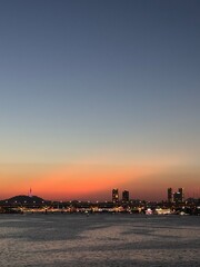 Fototapeta premium Vertical view of Seoul skyline and N Seoul Tower during vibrant orange sunset over Han River