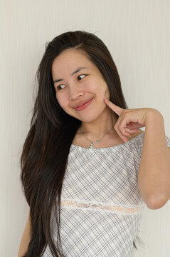 Young woman with long dark hair smiling thoughtfully in casual attire