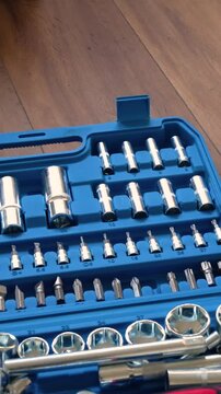 Hands opening a blue plastic toolbox with a professional socket wrench and screwdriver tool set inside, close-up of mechanic equipment for automotive repair and DIY maintenance