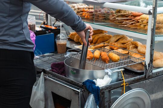 Street vendor preparing fried snacks in urban setting