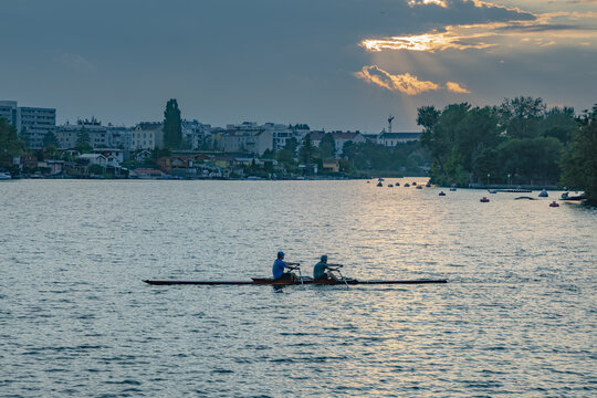Wien, Austria - 22 August 2024: View of two people rowing a boat on the Alte Donau with the city skyline in the background during golden hour.