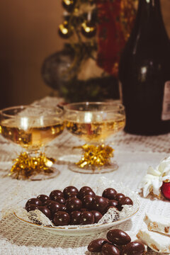 Festive table presenting two glasses of sparkling champagne alongside traditional nougat bars and rich chocolate almonds, symbolizing celebration during the holiday season.