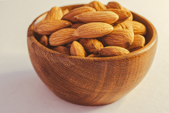 A rustic wooden bowl with raw, unsalted almonds, a nutrient-rich snack ideal for baking, cooking, as a topping, or for healthy diets.