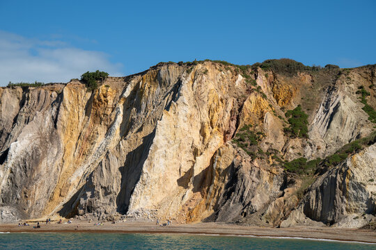 Alum Bay, England, United Kingdom - 05 September 2026: View of The Needles Landmark Attraction, featuring iconic multi-colored sand cliffs rising above the pebble beach under a clear sky.