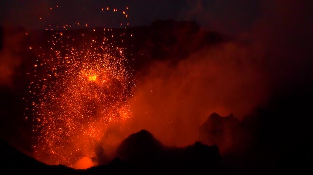 View of Stromboli volcano eruption at night with glowing lava flows in the darkness in Stromboli, Sicily, Italy.