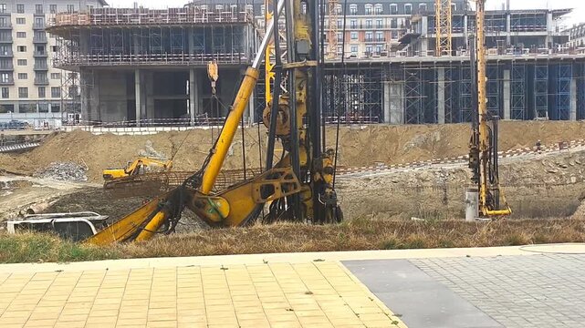Heavy construction machinery working at a large construction site in Baku, Azerbaijan, including an excavator and crane preparing the ground for a new building project.