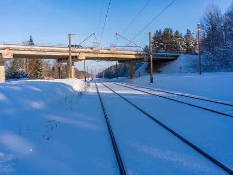 View of snow-covered railway tracks passing under a concrete bridge in a winter landscape with clear blue sky in Traku Voke, Vilnius, Vilniaus apskritis, Lithuania.