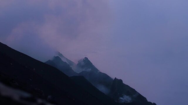 View of Stromboli volcano with volcanic smoke and clouds at dusk in Stromboli, Sicily, Italy.
