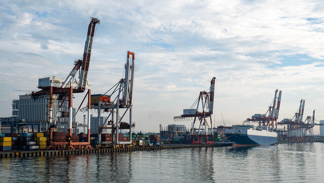 View of the Cebu Port Authority with large container cranes, stacks of shipping containers, and a cargo ship docked along the waterfront in Cebu City, Central Visayas, Philippines.