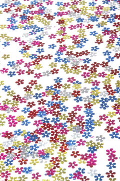 Flower sequins confetti pattern scattered on white background