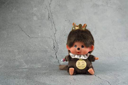 popular monkey classic doll toy , Monchichi or Monchhichi , Japanese cute pilot costume monkey fur doll display on stone table with grey wall background in souvenir tourist shop 50 years Anniversary