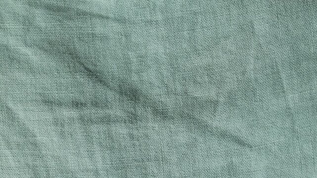 Crumpled green cotton fabric texture moving slowly in a detailed close-up shot showing its weave and creases