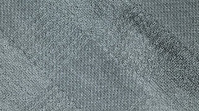 Gray terrycloth towel texture rotating in a macro close-up. Cotton fabric background with soft pile and geometric pattern