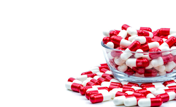 red pills. Red white antibiotic capsules pills in glass bowl and some on white background with copy space. Drug resistance concept. Antibiotics drug use with reasonable and global healthcare concept.