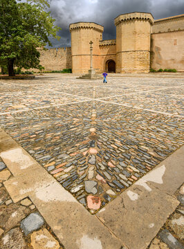 Traveler walking through Poblet Monastery historic square with ancient stone pavement and dark sky