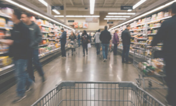 Blurred Motion of Customers Shopping with Cart in Grocery Store Aisle