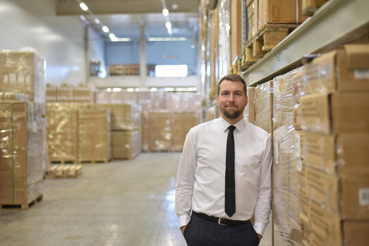 portrait friendly businessman/ manager in suit working in the warehouse of a company