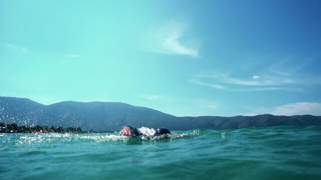 Swimmer Practicing Front Crawl Stroke In Open Sea Water Near Mountains Side. Triathlon Training