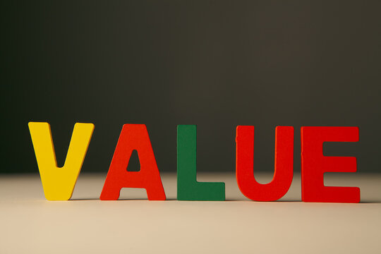 Wooden letters spelling the word value on white table.