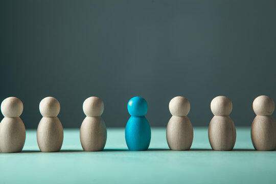 Leadership concept. Group of white wooden people standing in a row and one blue leader