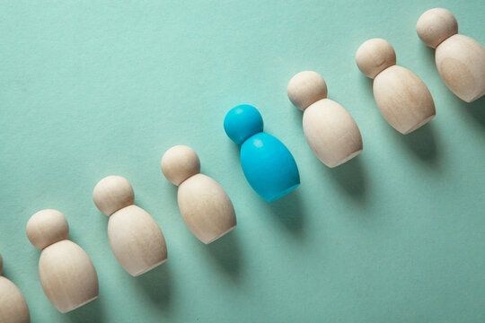Leadership concept. Group of white wooden people standing in a row and one blue leader