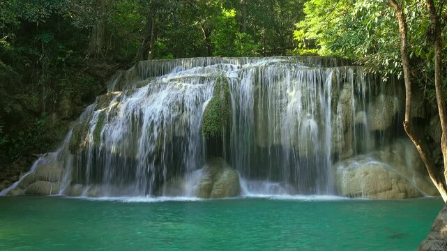 View of the cascading turquoise waters of Erawan Falls surrounded by dense tropical forest in Tha Kradan, Kanchanaburi, Thailand.