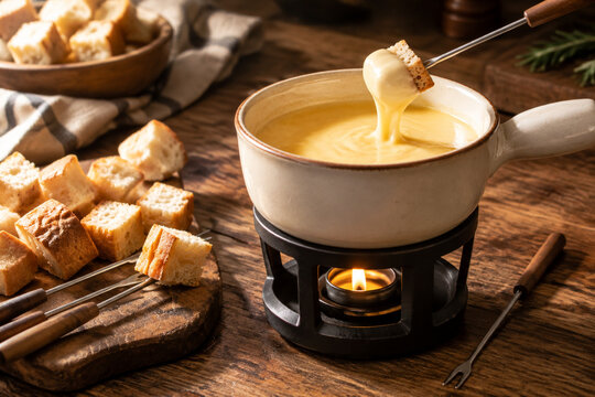 Ceramic fondue pot with melted cheese and bread skewers on rustic table, cozy cheese fondue dining concept