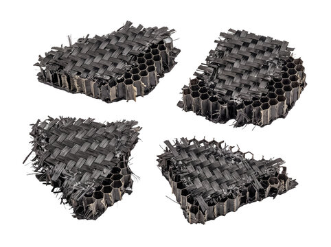 Carbon fiber honeycomb composite material broken damaged fragments isolated on black background, showing frayed woven carbon weave layer and exposed internal hexagonal core structure for industrial en