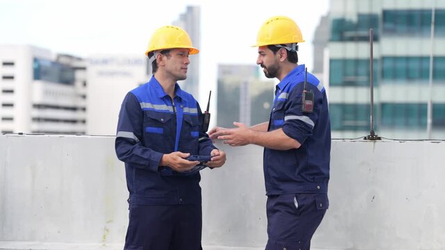 Construction worker hard hat uniform rooftop city communication safety discussion during urban building inspection teamwork near concrete barrier and exposed steel reinforcement