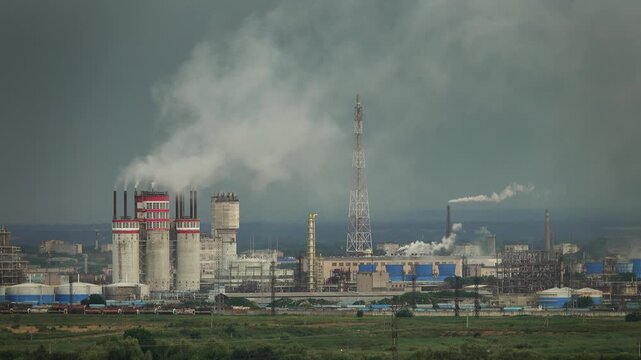 View of an industrial plant with tall smokestacks emitting smoke under a cloudy sky in Russia.