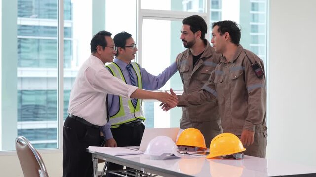 Businessman engineer construction worker handshake safety helmet meeting agreement collaboration workplace team planning project discussion around table for indoor building site safety coordination
