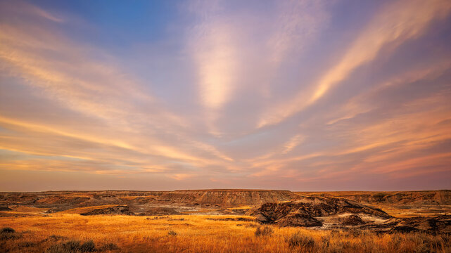 Golden Prairie Badlands Beneath a Dramatic Pink and Lavender Sunset Sky