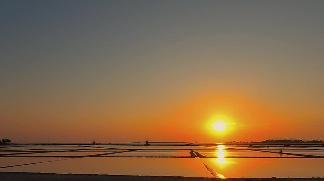 Golden sunset over tranquil salt pans near Trapani, Italy