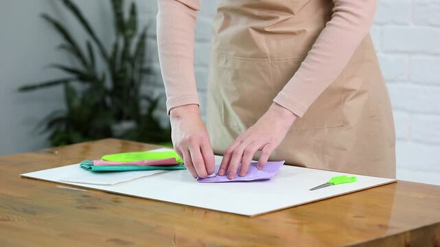 Woman unboxing purple padded bubble mailer envelope at wooden table. Opening protective package and removing small souvenir item. E commerce parcel delivery