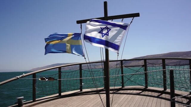 Israeli and Swedish Flags Waving by the Lake Under a Clear Blue Sky