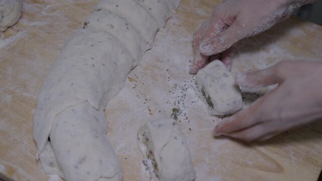 Hands pinch and seal dough around filling to make homemade savory pastries on a floured work surface.