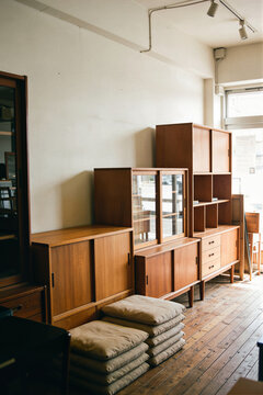 Second hand furniture store corner with plain wooden cabinets against the wall, cushions piled on the floor
